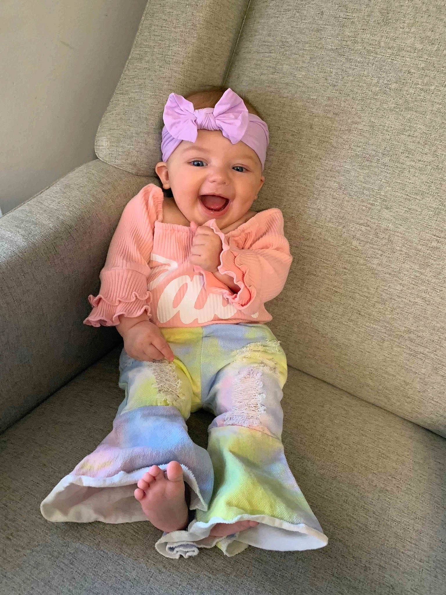 Kinlee is registered to the contest to win money with this photo: baby, baby_toddler_clothing, child, comfort, eye, fashion_accessory, foot, happy, headwear, human_body, human_leg, leg, linens, magenta, person, pink, sitting, sleeve, smile, t_shirt