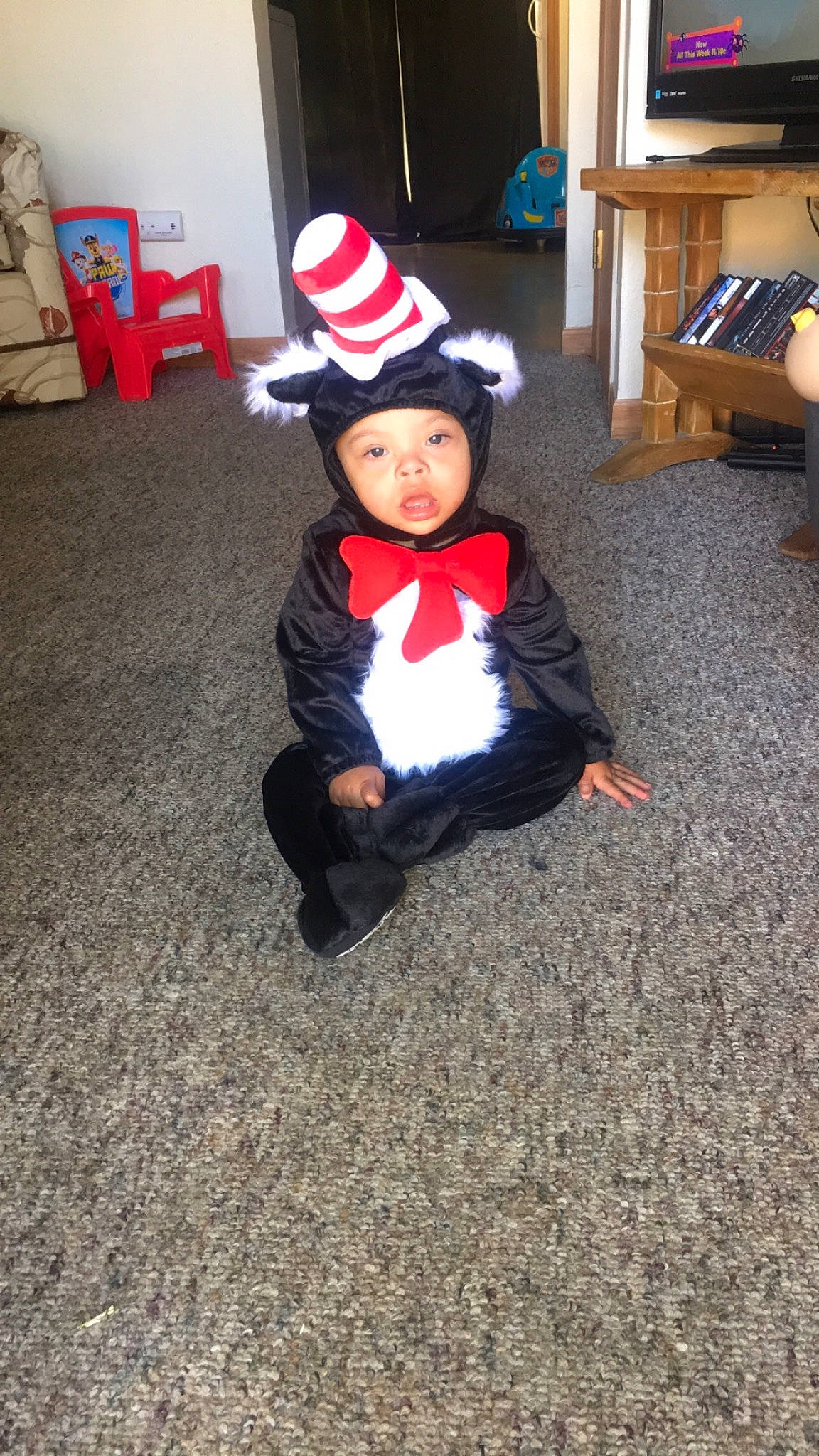 Landyn is registered to the contest to win money with this photo: baby, baby_toddler_clothing, carmine, chair, child, costume_hat, event, fictional_character, floor, flooring, fur, hat, headwear, holiday, human_body, lap, person, sitting, table, toddler