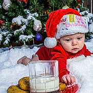 Kaylee joined the competition — help win amazing prizes! baby, santa_hat, christmas_tree, snow, cookies, milk, holiday, festive, child, winter, red_clothing, plate, glass, decoration, ornaments, pine_tree, celebration, cute, outdoor, seasonal