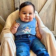 Junior joined the competition — help win amazing prizes! baby, blue_tank_top, casual, chair, child, clothing, cozy, cute, denim_jeans, face, fashion, happy, indoors, infant, person, plush_blanket, portrait, sitting, smiling, wooden_background