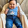 Junior joined the competition — help win amazing prizes! baby, baby_shoes, blue_shirt, child, clothing, comfortable, cozy, cute, denim_jeans, face, farm_animals, furniture, happy, indoor, person, plush_blanket, portrait, sitting, smiling, wooden_chair
