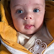 ézekiel participe au concours pour gagner de l'argent avec cette photo : baby, blue_eyes, child, close_up, curious, cute, expression, face, human, indoors, infant, pacifier, person, portrait, soft_texture, tongue_out, warm_clothing, white_jacket, yellow_jacket, young_child