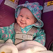 Mazelyn joined the competition — help win amazing prizes! apparel, baby, baby_clothes, blanket, car_seat, child, child_safety, cozy, cute, face, happy, heart_pattern, hooded_jacket, indoor, infant, portrait, safety, seatbelt, smiling, warm