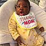 baby, child, infant, onesie, yellow_clothing, bib, thanks_mom, baby_seat, blanket, expression, surprised, indoor, soft_texture, cushion, human, person, cute, portrait, skin, hand