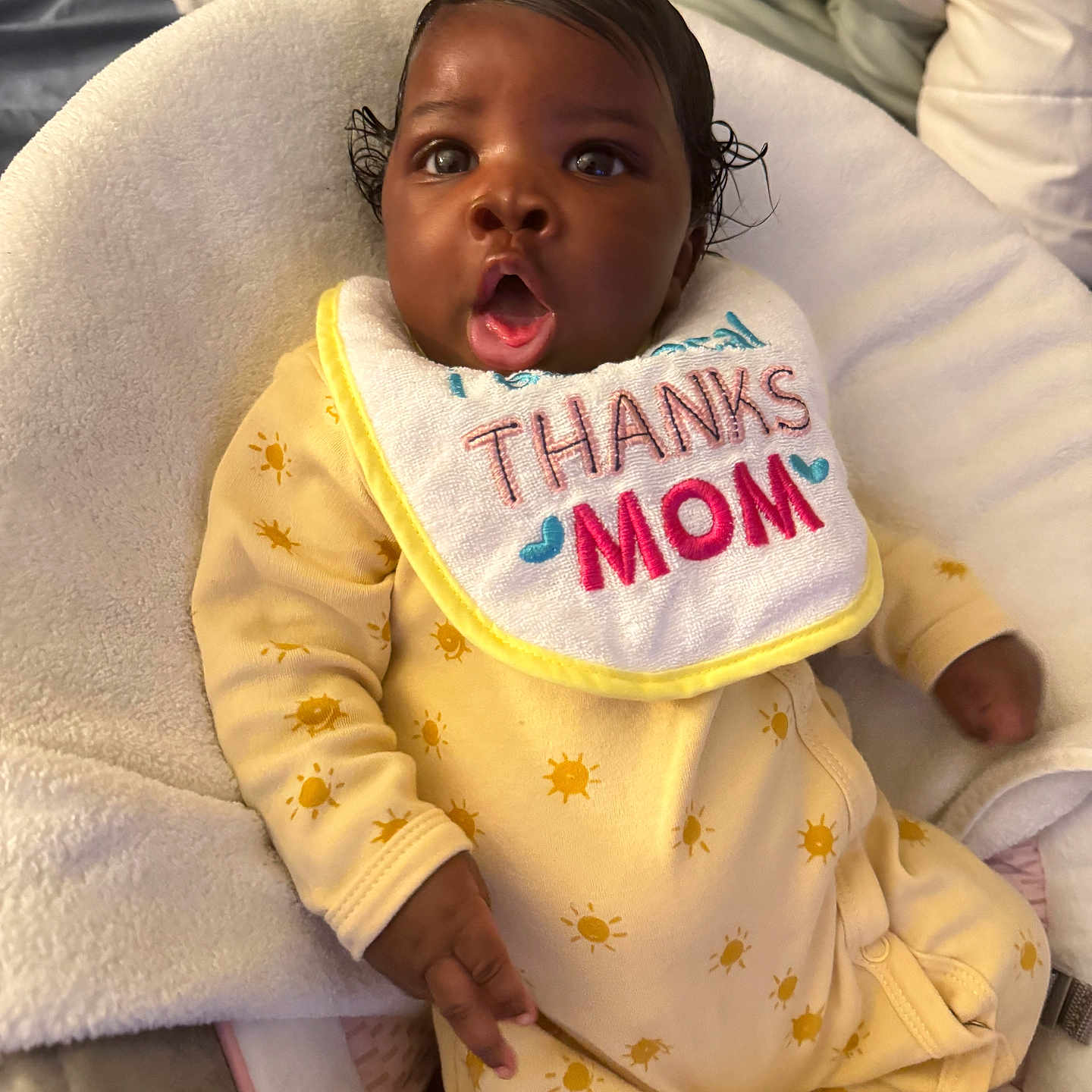 Maelise is registered to the contest to win money with this photo: baby, baby_seat, bib, blanket, child, cushion, cute, expression, hand, human, indoor, infant, onesie, person, portrait, skin, soft_texture, surprised, thanks_mom, yellow_clothing