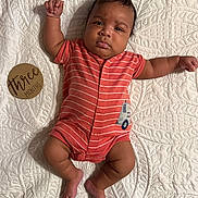 Mazi joined the competition — help win amazing prizes! baby, infant, three_months, onesie, striped_clothing, raised_arm, lying_down, quilt, textured_bedspread, wooden_sign, curious_expression, cute, child, newborn, indoors, soft_lighting, skin, foot, hand, face