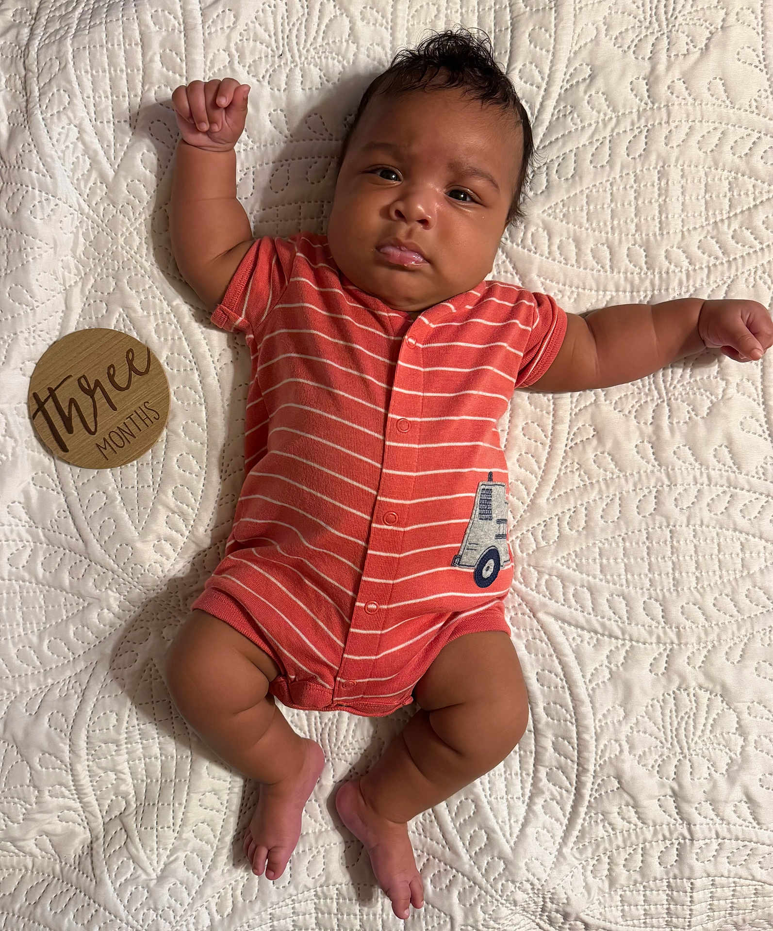 Mazi joined the competition — help win amazing prizes! baby, infant, three_months, onesie, striped_clothing, raised_arm, lying_down, quilt, textured_bedspread, wooden_sign, curious_expression, cute, child, newborn, indoors, soft_lighting, skin, foot, hand, face