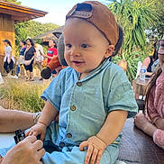 énaël participe au concours pour gagner de l'argent avec cette photo : baby, child, cap, outdoor, people, hand, blue_clothing, smiling, grass, trees, wood, table, glasses, person, vape, sitting, daylight, nature, casual, happy