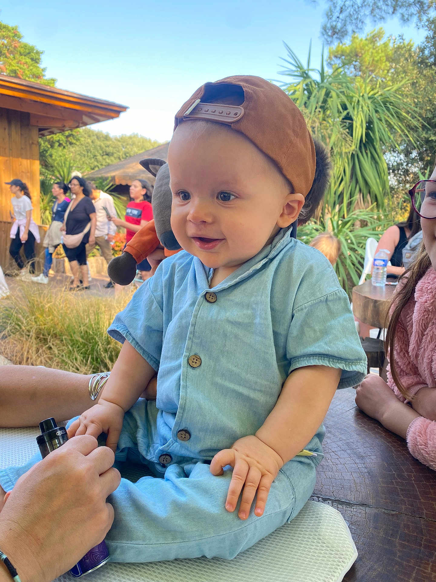 énaël participe au concours pour gagner de l'argent avec cette photo : baby, child, cap, outdoor, people, hand, blue_clothing, smiling, grass, trees, wood, table, glasses, person, vape, sitting, daylight, nature, casual, happy