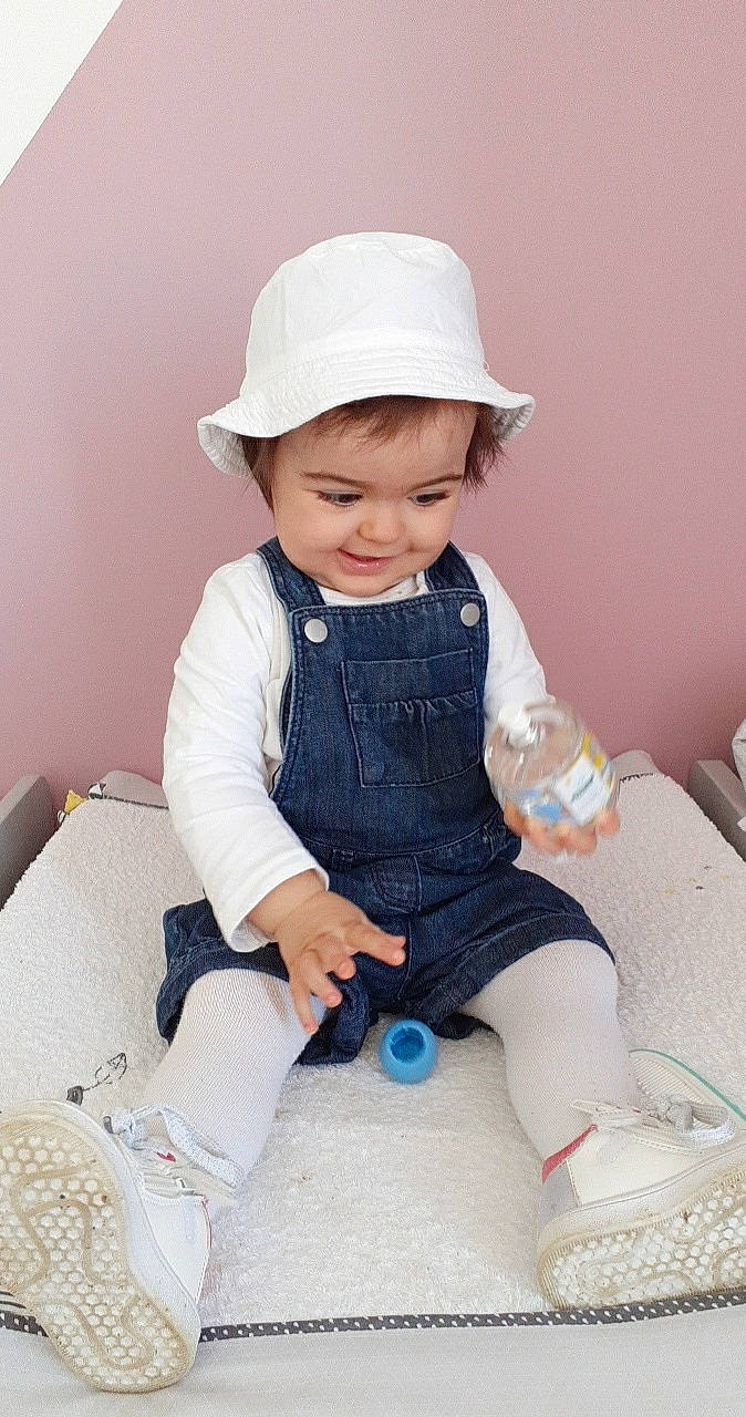 Naëlya participe au concours pour gagner de l'argent avec cette photo : baby, baby_toddler_clothing, cap, cheek, electric_blue, fun, happy, hat, headgear, human_body, joy, outerwear, pattern, person, pink, skin, sleeve, smile, sun_hat, t_shirt
