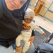 Kai Green joined the competition — help win amazing prizes! adult, child, baby, beanie, black_hoodie, blue_jeans, car_seat, clothing, floor, hand, indoor, person, plush_boots, sitting, stroller, waiting_room, window, teddy_bear_patch, warm_clothes, wooden_podium