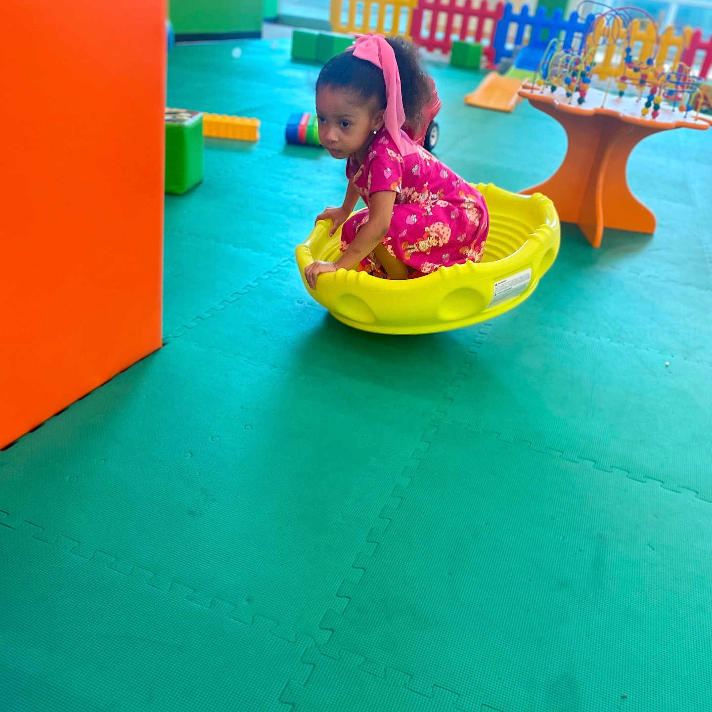 Simone Garrett joined the competition — help win amazing prizes! active, candid, child, colorful, curly_hair, dress, floor_mat, fun, girl, headband, indoor, pink, plastic_toy, play_area, play_equipment, playground, puzzle_mat, toy, yellow, young_child