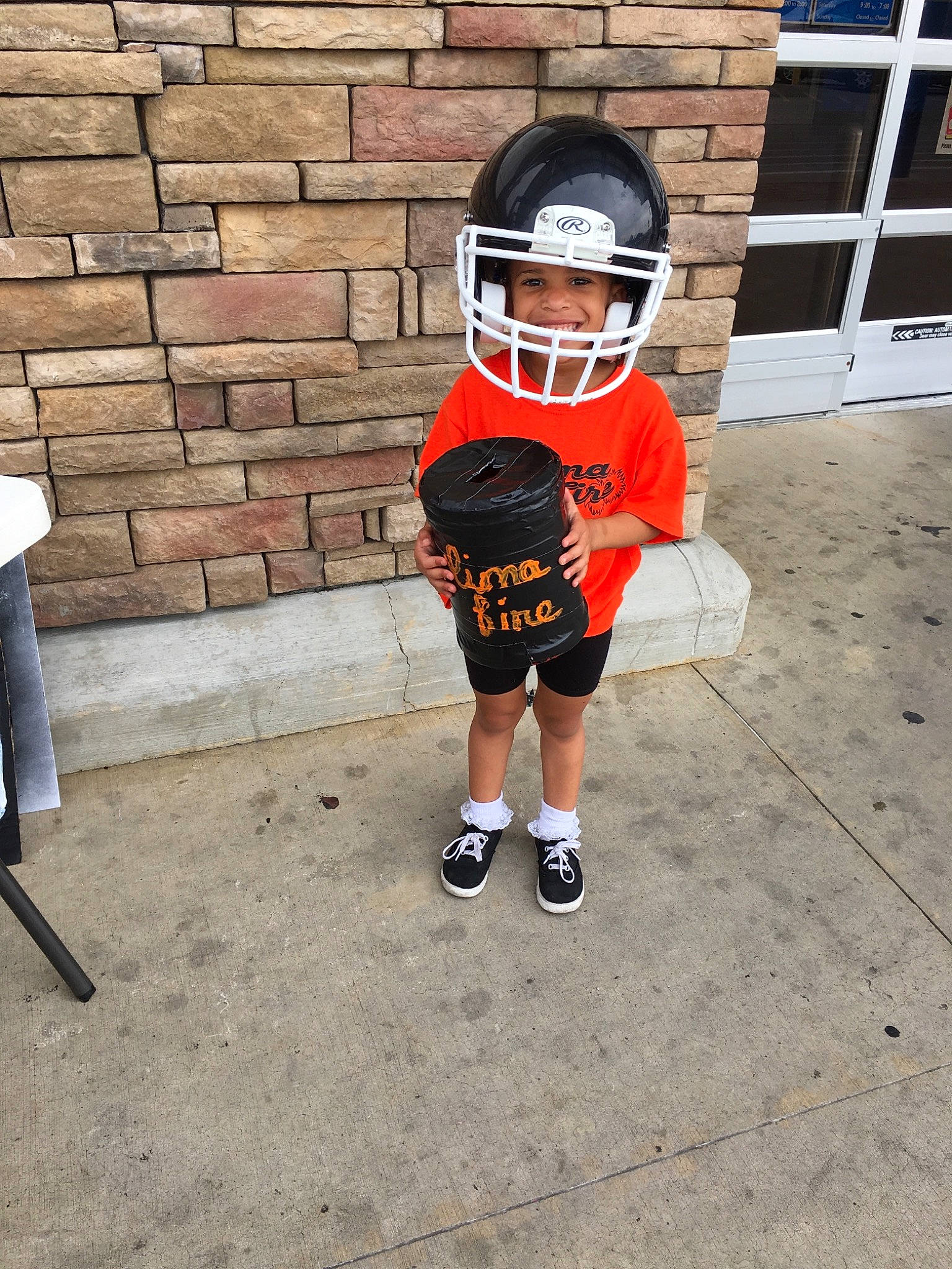Sloan is registered to the contest to win money with this photo: american_football, ball, child, costume, footwear, glasses, headgear, headwear, helmet, joy, leg, person, personal_protective_equipment, play, recreation, shoe, sports_gear, t_shirt, toddler, vacation