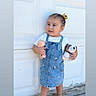 Naylan is registered to the contest to win money with this photo: toddler, child, denim_dress, yellow_sandals, hair_bow, doll, stuffed_animal, outdoor, sidewalk, garage_door, cute, portrait, standing, casual, summer, playful, person, toy, happy, fashion