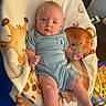 baby, infant, onesie, blanket, giraffe, bear, animal_print, cute, child, face, smiling, furniture, indoors, person, blue_clothing, soft_texture, lying_down, young_child, happy, cozy