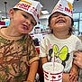 Miley is registered to the contest to win money with this photo: child, kids, smiling, restaurant, fast_food, in_n_out, burger, paper_hat, happy, messy_face, drink_cup, fries, table, casual_clothing, indoor, food, friendship, cute, portrait, family