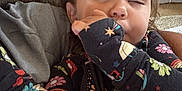 Miley is registered to the contest to win money with this photo: toddler, child, sleepy, onesie, patterned_clothing, couch, blanket, indoor, face, hand, hair, person, comfort, cozy, resting, casual, home, young_child, expression, relaxation