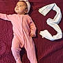 baby, pink_onesie, headband, maroon_blanket, white_cloth, number_three, infant, lying_down, cute, portrait, child, soft_texture, indoors, looking_away, small_hand, footed_pajamas, blanket, fabric, resting, young_child