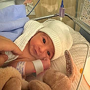 Ambre a rejoint le concours — aidez-le/la à gagner de superbes lots ! newborn, baby, hospital, crib, blanket, hat, plush_toy, bunny, infant, wrapping, bed, hand, medical_band, soft_toy, cute, child, person, indoors, resting, cozy