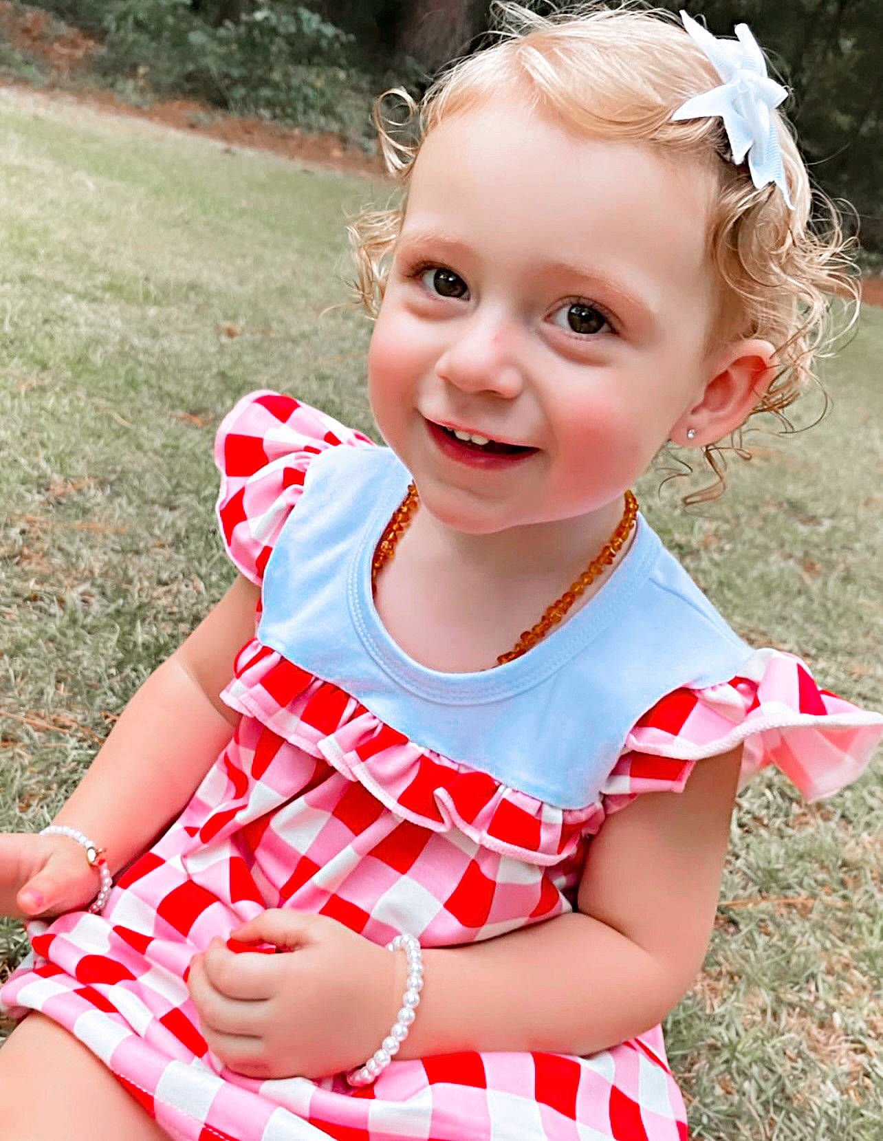 Brayley is registered to the contest to win money with this photo: baby_toddler_clothing, dress, eye, face, facial_expression, grass, hairstyle, hand, happy, head, human_body, joy, lip, organ, people_in_nature, person, photograph, pink, plant, skin