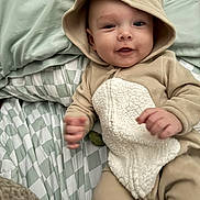 Myles joined the competition — help win amazing prizes! baby, infant, child, onesie, hood, antlers, bed, blanket, pattern, smile, cute, soft, hands, lying_down, cozy, indoor, sleepwear, young, person, portrait