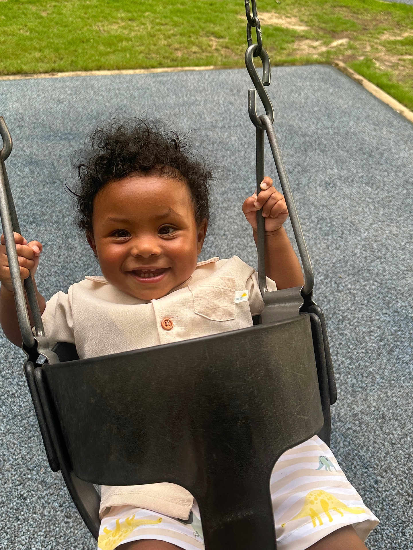 Maximo is registered to the contest to win money with this photo: toddler, child, swing, playground, smiling, curly_hair, outdoor, grass, metal_chain, clothing, shorts, seat, happy, baby, person, play, fun, summer, park, cute