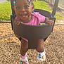 toddler, swing, playground, smiling, child, outdoor, grass, woodchips, pink_clothing, shoes, beads, hair, person, happy, summer, sunlight, park, play, fun, joy