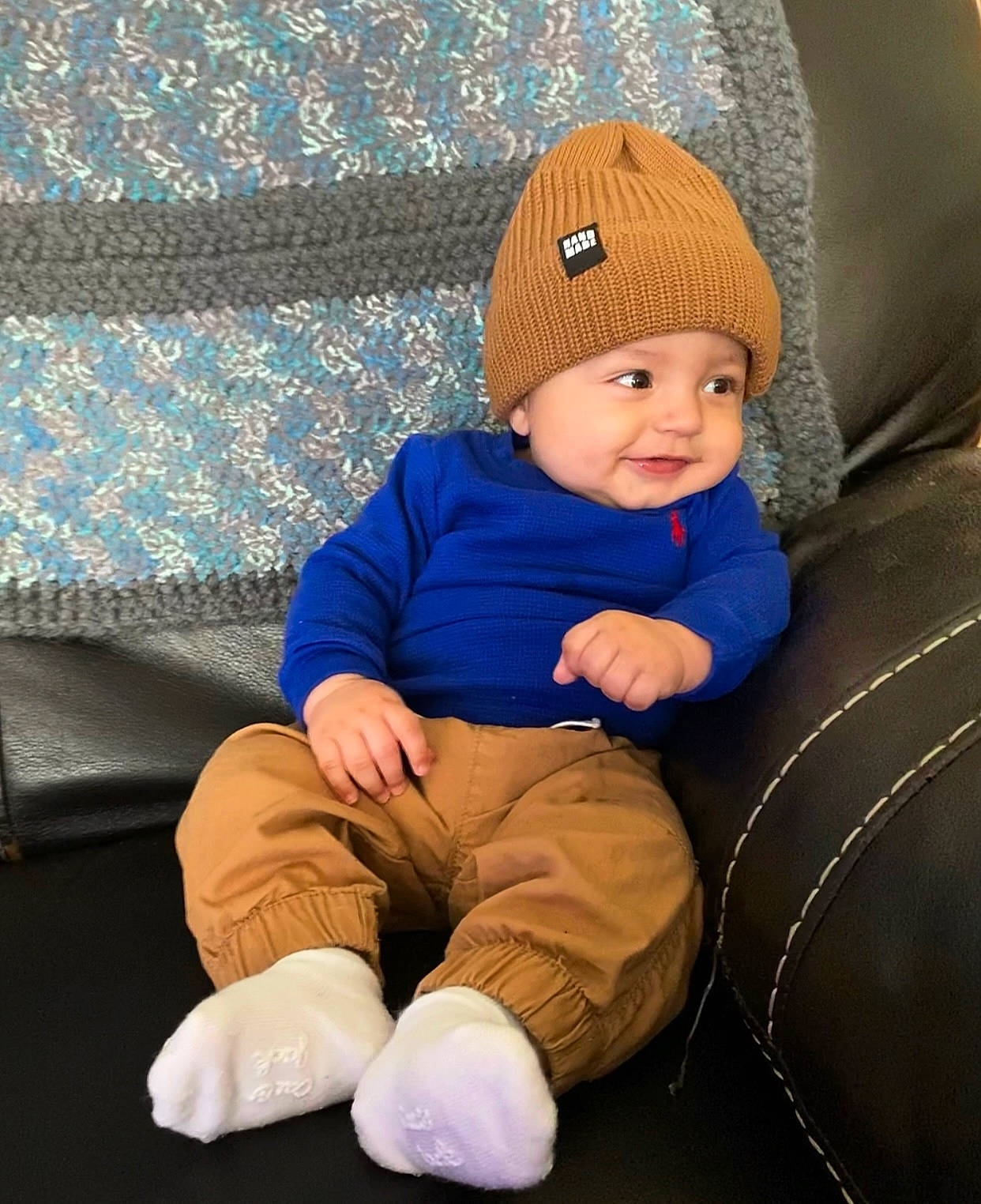 Amani is registered to the contest to win money with this photo: baby, baby_toddler_clothing, beanie, blue, cap, cheek, child, comfort, couch, electric_blue, fashion_accessory, fun, headwear, joy, knit_cap, lap, outerwear, person, purple, sitting