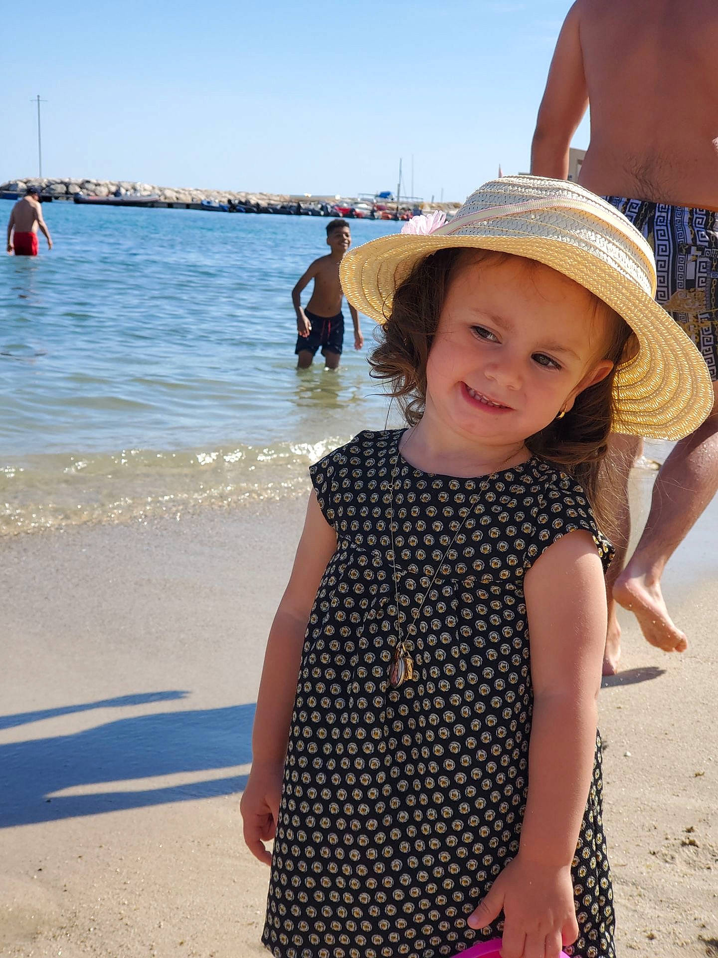 Tess participe au concours pour gagner de l'argent avec cette photo : azure, beach, blue, fun, happy, hat, headwear, joy, leisure, morning, people_on_beach, person, skin, sky, sleeve, smile, sun_hat, toddler, travel, vertebrate