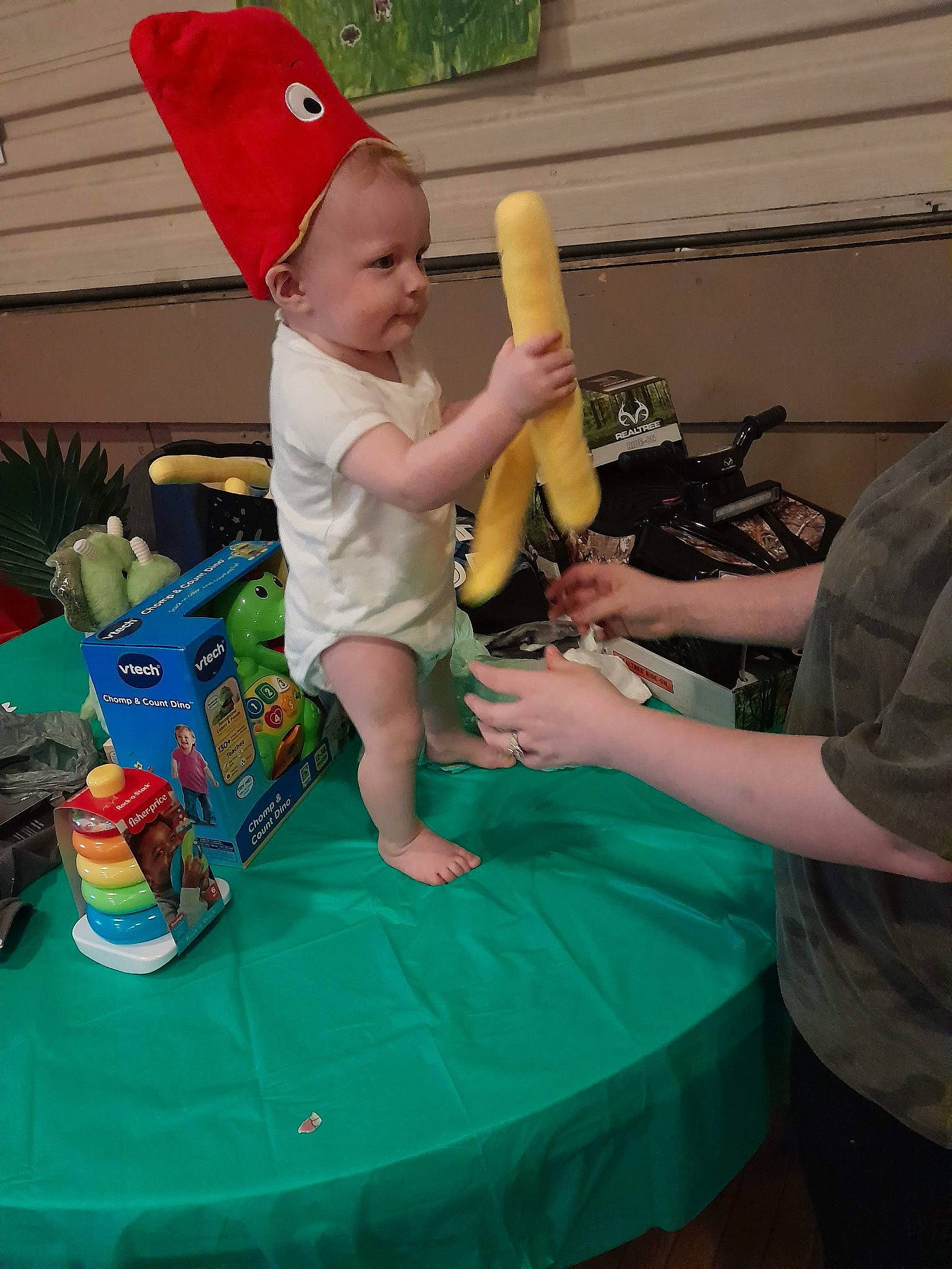 Dawson is registered to the contest to win money with this photo: baby, baseball_cap, cap, child, event, fun, grass, holiday, lap, lawn_ornament, leisure, person, plastic, play, recreation, room, shorts, sitting, t_shirt, toddler