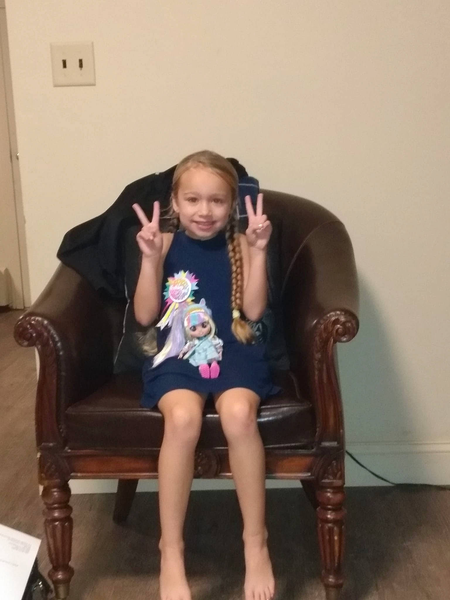 Blythe is registered to the contest to win money with this photo: brown_hair, chair, comfort, door, face, fashion_design, floor, flooring, furniture, hardwood, human_leg, joy, knee, leg, leisure, long_hair, person, shoe, sleeve, smile