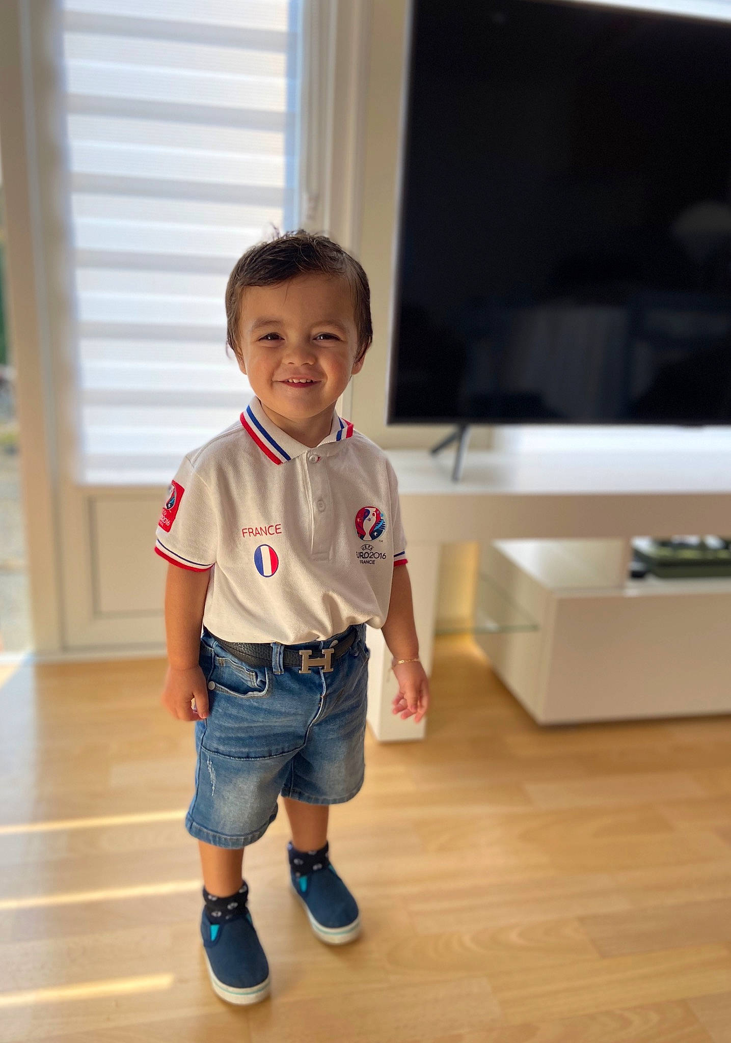 Varane participe au concours pour gagner de l'argent avec cette photo : baby_toddler_clothing, child, denim, entertainment_center, flat_panel_display, flooring, fun, happy, hardwood, head, home_appliance, jeans, joy, leg, person, sleeve, smile, television, television_set, thumb