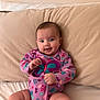 Aixa is registered to the contest to win money with this photo: baby, infant, child, onesie, butterfly, purple_clothing, pillow, beige, smile, hand, face, cute, indoors, portrait, sitting, skin, young_child, person, happy, head