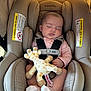 baby, sleeping, car_seat, plush_toy, giraffe, child, infant, seatbelt, pink_clothing, white_socks, comfort, peaceful, cushion, fabric, head_support, closeup, indoors, seat, resting, adorable