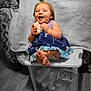 toddler, child, laughing, holding_object, sitting, plastic_container, indoor, floor, wooden_floor, dress, color_pop, blanket, fan, toy, happy, cute, foot, smiling, person, home