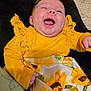 Gracelyn is registered to the contest to win money with this photo: baby, cheerful, child, closeup, cute, dress, face, hands, happy, headband, indoors, infant, lace, laughing, portrait, smiling, soft_surface, sunflower_pattern, yellow_clothing, young_child