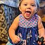 toddler, child, smiling, dress, indoor, toy, happy, playful, hair, pony_tail, colorful_clothing, patterned, wooden_floor, furniture, cute, young_child, portrait, person, baby, fun