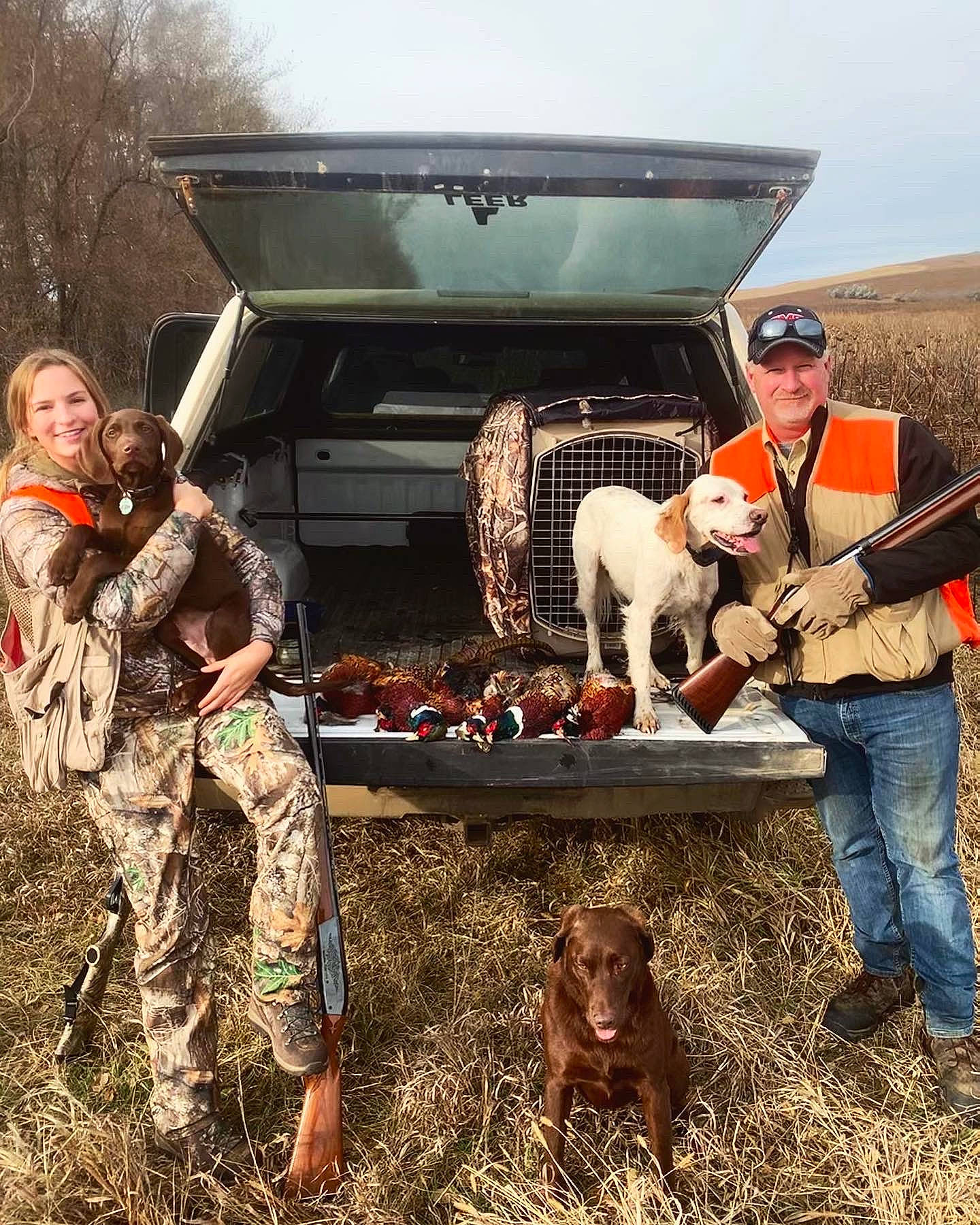 Fitzgerald is registered to the contest to win money with this photo: automotive_exterior, camouflage, car, carnivore, dog, dog_breed, fawn, grass, hat, mammal, marines, military_camouflage, motor_vehicle, sky, smile, tire, tree, vehicle, wheel, working_animal