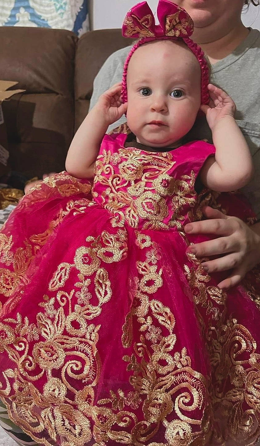 Mamie is registered to the contest to win money with this photo: baby, baby_toddler_clothing, beauty, child, day_dress, dress, event, eye, face, fashion_design, formal_wear, happy, magenta, one_piece_garment, person, pink, red, skin, sleeve, textile