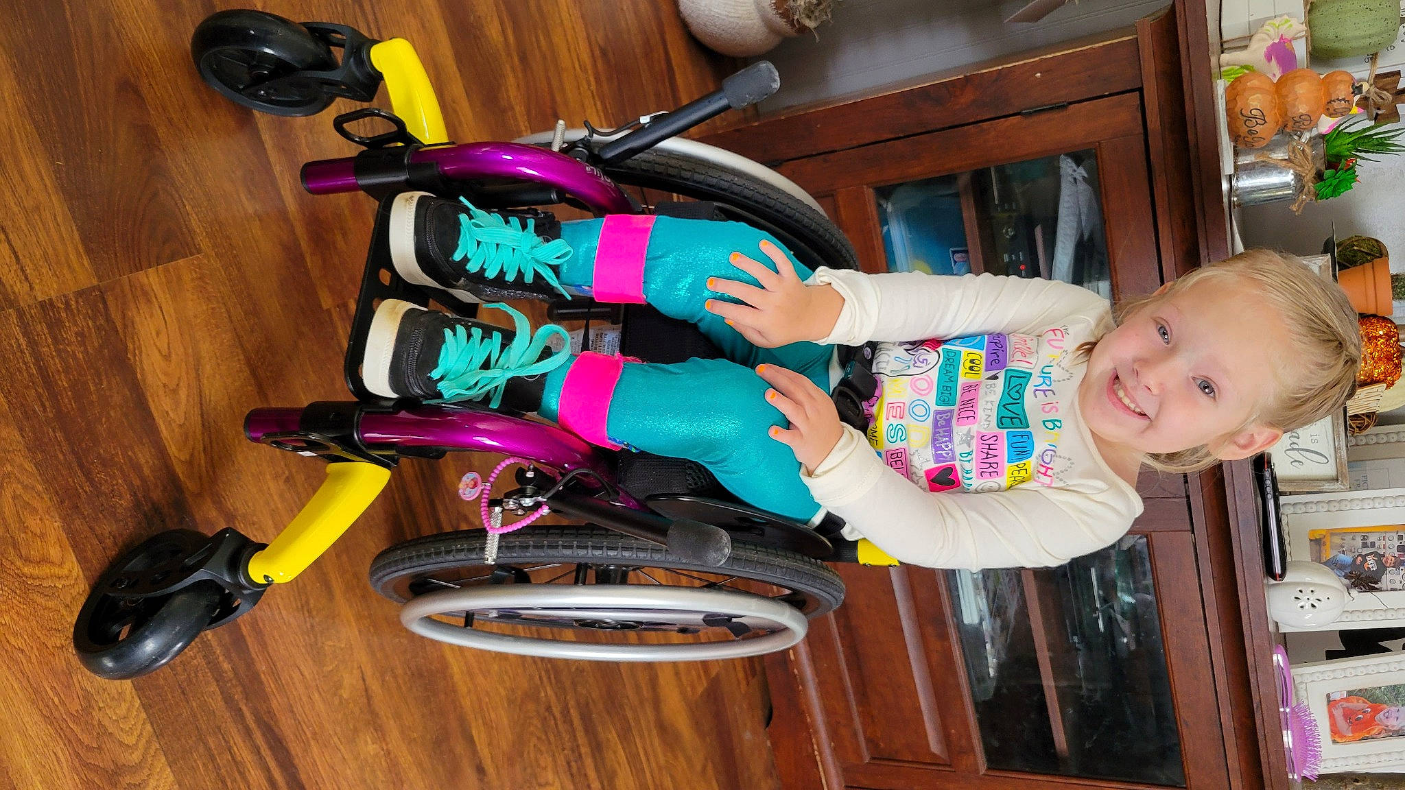 Montana is registered to the contest to win money with this photo: baby, baby_products, baby_toddler_clothing, bookcase, cabinetry, child, fun, hardwood, joy, magenta, outdoor_shoe, person, room, shelf, smile, t_shirt, thigh, tire, toddler, toy