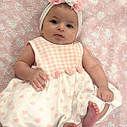 Aria is registered to the contest to win money with this photo: baby, infant, child, dress, headband, flower, pink, white, heart_pattern, blanket, soft_texture, cute, lying_down, feet, hand, face, portrait, adorable, skin, person