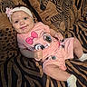 baby, infant, child, pink_clothing, headband, flower, smile, cute, lying_down, zebra_pattern, blanket, pillow, animal_print, soft_toys, socks, indoors, portrait, happy, face, person