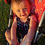 toddler, child, stroller, outdoor, sunlight, grass, blue_eyes, smiling, happy, playing, summer, rainbow_pattern, clothing, skin, baby, foot, hand, seat, closeup, portrait