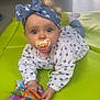 baby, pacifier, headband, blue, heart_pattern, mat, green, toy, cloth_book, indoor, floor, child, cute, infant, clothing, play, face, eyes, hand, toddler