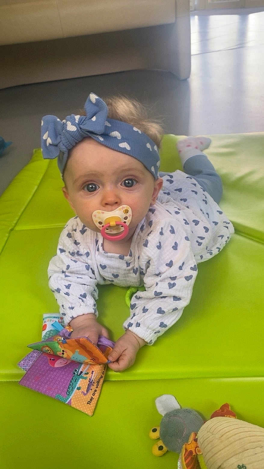 Mya participe au concours pour gagner de l'argent avec cette photo : baby, pacifier, headband, blue, heart_pattern, mat, green, toy, cloth_book, indoor, floor, child, cute, infant, clothing, play, face, eyes, hand, toddler