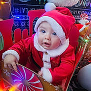 Zack is registered to the contest to win money with this photo: baby, child, santa_hat, red_clothing, holiday, christmas_lights, festive, toy, decorations, indoor, cheerful, cute, holiday_season, winter, celebration, sleigh, plush, smiling, face, seasonal