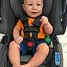 Kyro is registered to the contest to win money with this photo: baby, car_seat, smiling, child, infant, safety_harness, orange_shirt, blue_shorts, indoor, cute, person, seat, happy, footwearless, head, face, skin, toy, photography, seatbelt