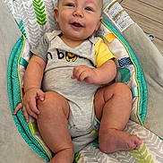 Kyro is registered to the contest to win money with this photo: baby, infant, smile, happy, child, face, sitting, onesie, baby_seat, pattern, leaf_pattern, fabric, foot, hand, skin, indoor, floor, tile_floor, cute, comfort