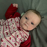 Lottie-May joined the competition — help win amazing prizes! baby, infant, child, face, eyes, clothing, red_sleeves, patterned_dress, lying_down, blanket, toy, purple_toy, indoor, portrait, cute, young, skin, head, hand, expression