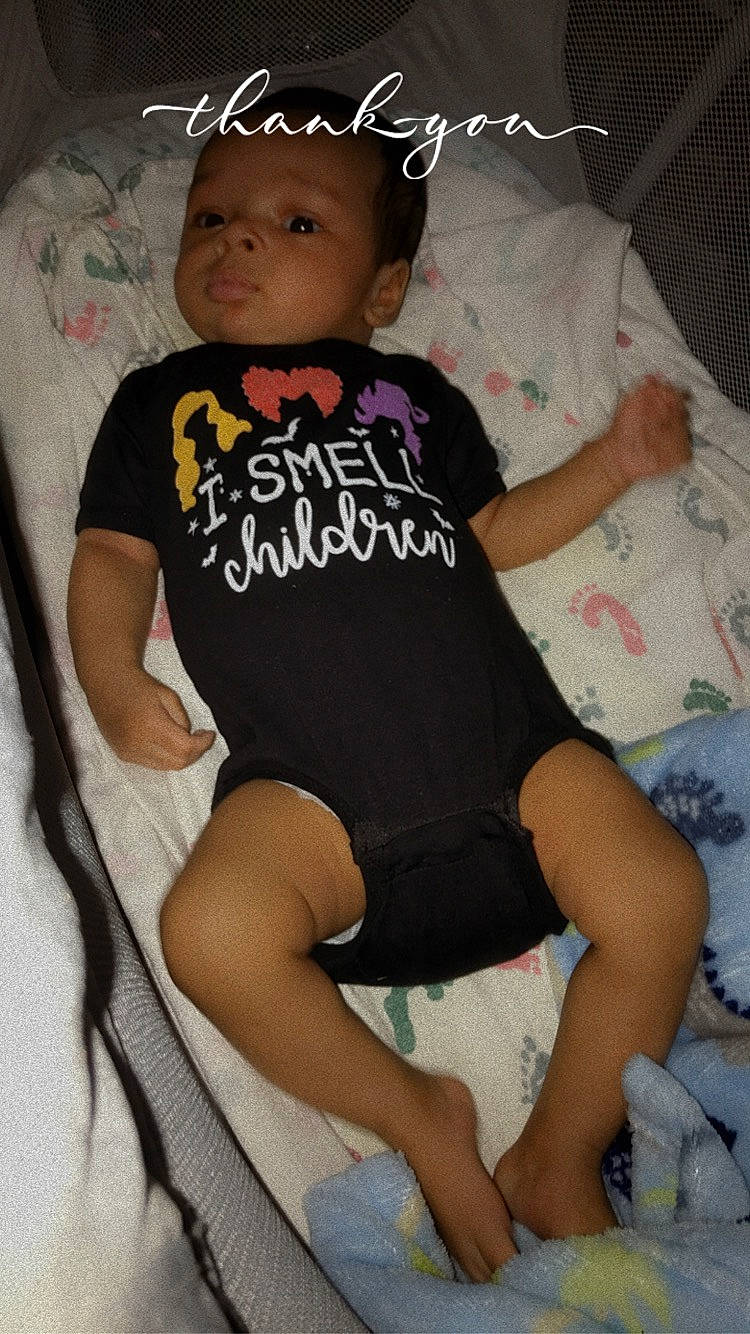 Jeremiah is registered to the contest to win money with this photo: baby_toddler_clothing, child, comfort, finger, happy, hat, headgear, human_leg, knee, lap, leg, linens, person, pink, shorts, skin, sleeve, t_shirt, thigh, toddler